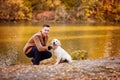 Man walking with dog in autumn Park by river. Royalty Free Stock Photo