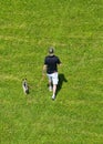 Man Walking Dog in a Grassy Field Royalty Free Stock Photo
