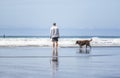 A man walking a dog on the shore of the Northwest Pacific