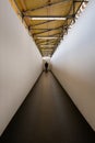 Man walking down a corridor towards a well lit end exit Royalty Free Stock Photo