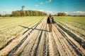 A man walking down a dirt road among fields, horizon and blue sky Royalty Free Stock Photo
