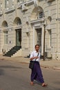 A man walking down the street in Yangon wearing traditional Burmese longyi