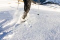 Man running downhill through deep snow with snoeshoes and hiking sticks.