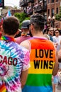 Man walking with friends at Gay Pride parade is wearing a rainbow colored shirt that reads `Love Wins`