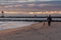 A man walking his dog along the beach at sunrise Royalty Free Stock Photo