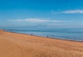 A man walking his dog on Ramsgate, Kent, Main Sands beach on a bright blue winter day