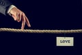 Man walking his fingers along a length of rope towards Love