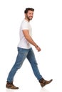 Young Man In Jeans And White T-shirt Is Walking And Looking At Camera Side View Royalty Free Stock Photo