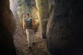 Man walking on narrow footpath between stone columns in sandstone rocks