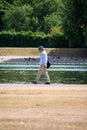 Man walking next to a pond in Hyde Park in London, vertical