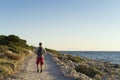 Man walking outdoors on road close ocean looking at sun going down