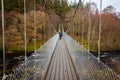 Man walking over an old wooden suspension bridge across a river in Scotland Royalty Free Stock Photo