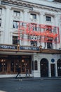 Man walking past Mousetrap neon sign on the facade of St Martins Theatre in London, UK