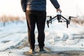 Man walking and preparing white drone with digital camera for flying