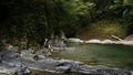 Man walking on the rocky river in paradise place. Creative. Woman cooling her feet in cld mountain stream.