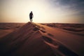 Man walking on sand dune against sunset