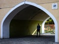 A man walking through the shadowy archway in a historical building. Karlowice district, WrocÃâaw, Poland.