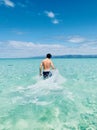 A man walking in the shallow ocean with turqouise blue water at summer.