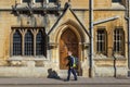 Man walking on sidewalk in front of an old building of Oxford Un