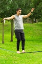 Man walking on slackline in park with arms out