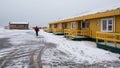 Man walking on a snowy road to the yellow winter cottage house in Iceland
