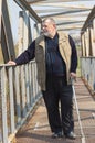 Man with walking stick standing on an metal bridge over small river Sura in Ukraine