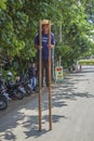 Man walking on stilts along roadside in Denpasar, Bali, Indonesia.