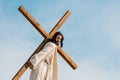 Man walking with wooden cross against sky and clouds Royalty Free Stock Photo