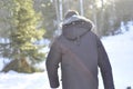 Man walking in the woods on a snowy path wearing a warm winter coat. Remote country road is idyllic for hiking.Man walking in the Royalty Free Stock Photo