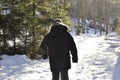 Man walking in the woods on a snowy path wearing a warm winter coat. Remote country road is idyllic for hiking.Man walking in the Royalty Free Stock Photo