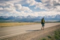 Man walks along an asphalt road with a backpack