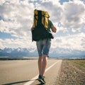 Man walks along an asphalt road with a backpack