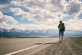 A man walks along an asphalt road overlooking the mountains