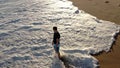 A man walks along the beach and stops. Shooting from above using a drone