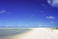 A man walks along a white sandy beach next to a turquoise lagoon on the island of Fakarava in the South Pacific