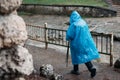 man walks in a blue raincoat in the rain. view from the back