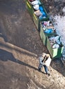 Man walks with a carton box along the overloaded dumpsters in winter street Royalty Free Stock Photo