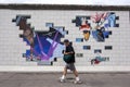 A man walks a colourful mural covering a section of the former infamous Berlin Wall in Germany. Royalty Free Stock Photo