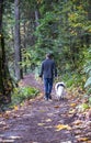 Man walks with dog along forest path breathing in fresh healthy air