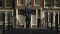 Man walks dog over footbridge on Brouwersgracht Canal in Amsterdam