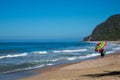 A man walks down the sandy beach holding a rainbow umbrella on the coast of the Pacific Coast Royalty Free Stock Photo