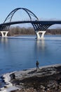 Man walks frozen shoreline under Lake Champlain Bridge Royalty Free Stock Photo