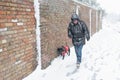 A man walks his dog in driving snow