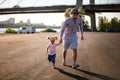 Man walks with his little cute daughter on the background of the city bridge