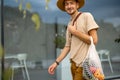 Man walks with a mesh bag full of fresh vegetables outdoors