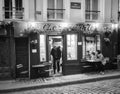 Man walks out door of Chez Marie Restaurant on Montmartre, Paris. Black and white photo.