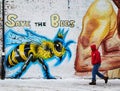 Man walks past a Save the Bees wall mural Royalty Free Stock Photo