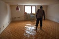 Man walks with rubber boots in a flooded basement room during flood