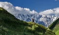 Man walks on a slope against the backdrop of Mount Shkhara, Uzhguli, Svaneti, Georgia