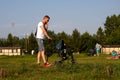 A man walks with a stroller and talks on the phone in a meadow with resting people and wild gophers on a sunny summer day